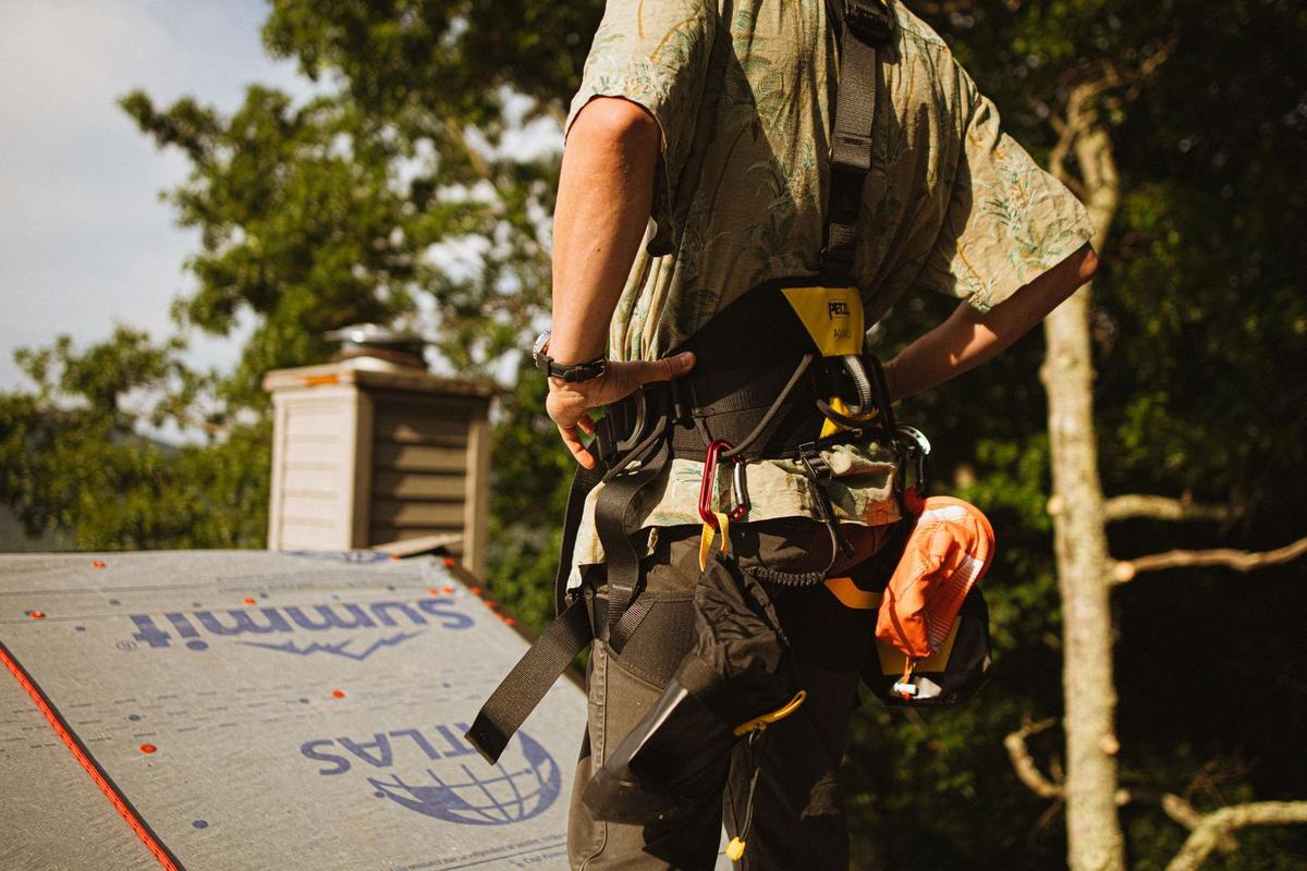 A roofer in a safety harness on a roof