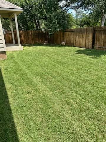Same backyard freshly mowed with clean stripe pattern