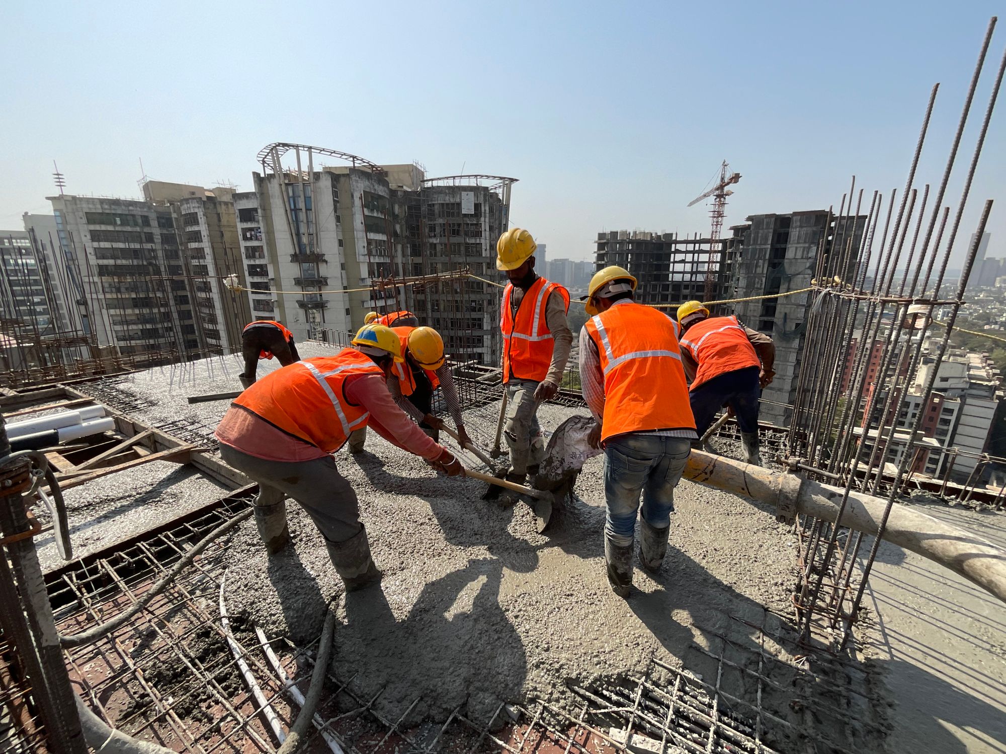 Concrete crew placing pumped concrete on a bright job site under a clear sky