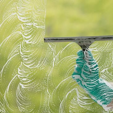 Hand cleaning a window with a squeegee
