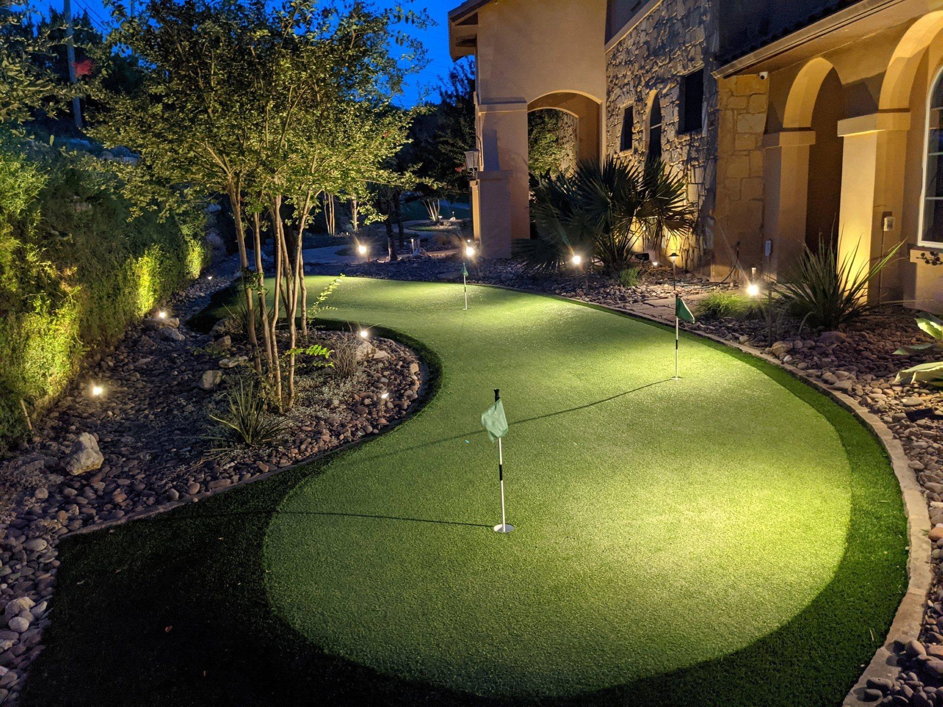Lit artificial putting green beside a Houston home