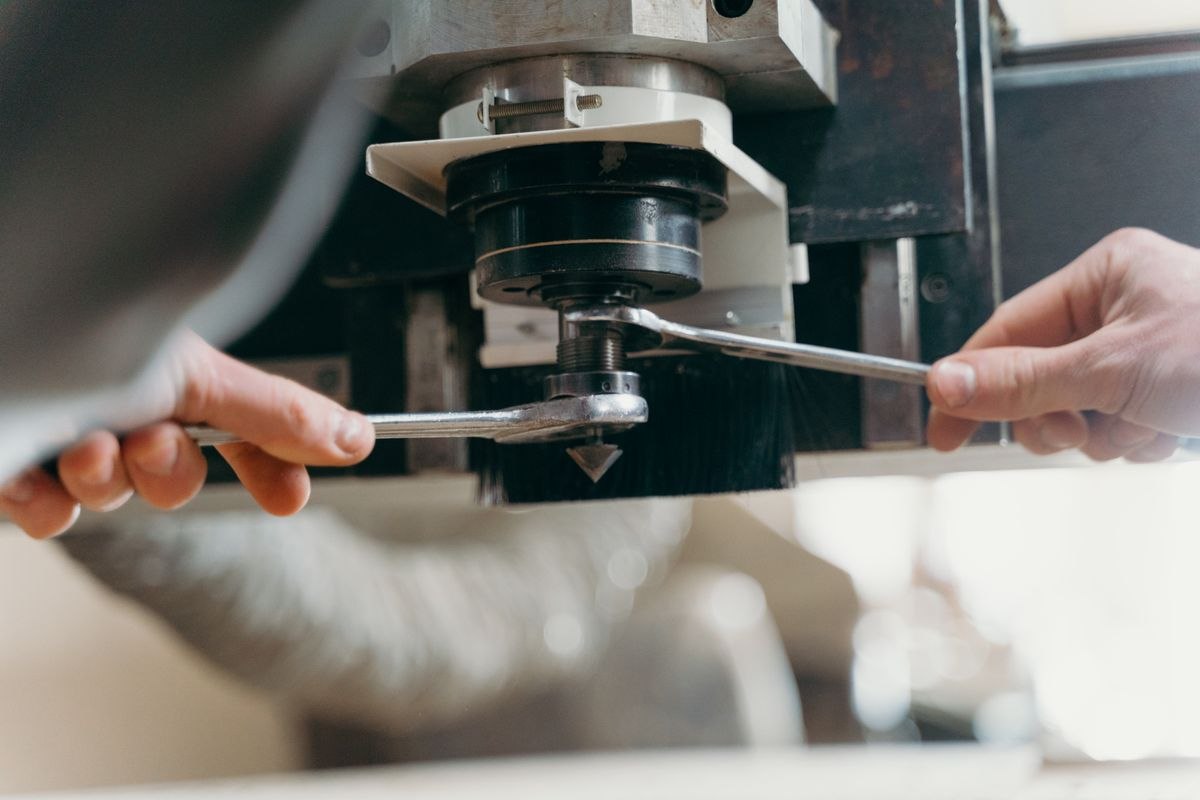 Hands using a wrench on industrial equipment