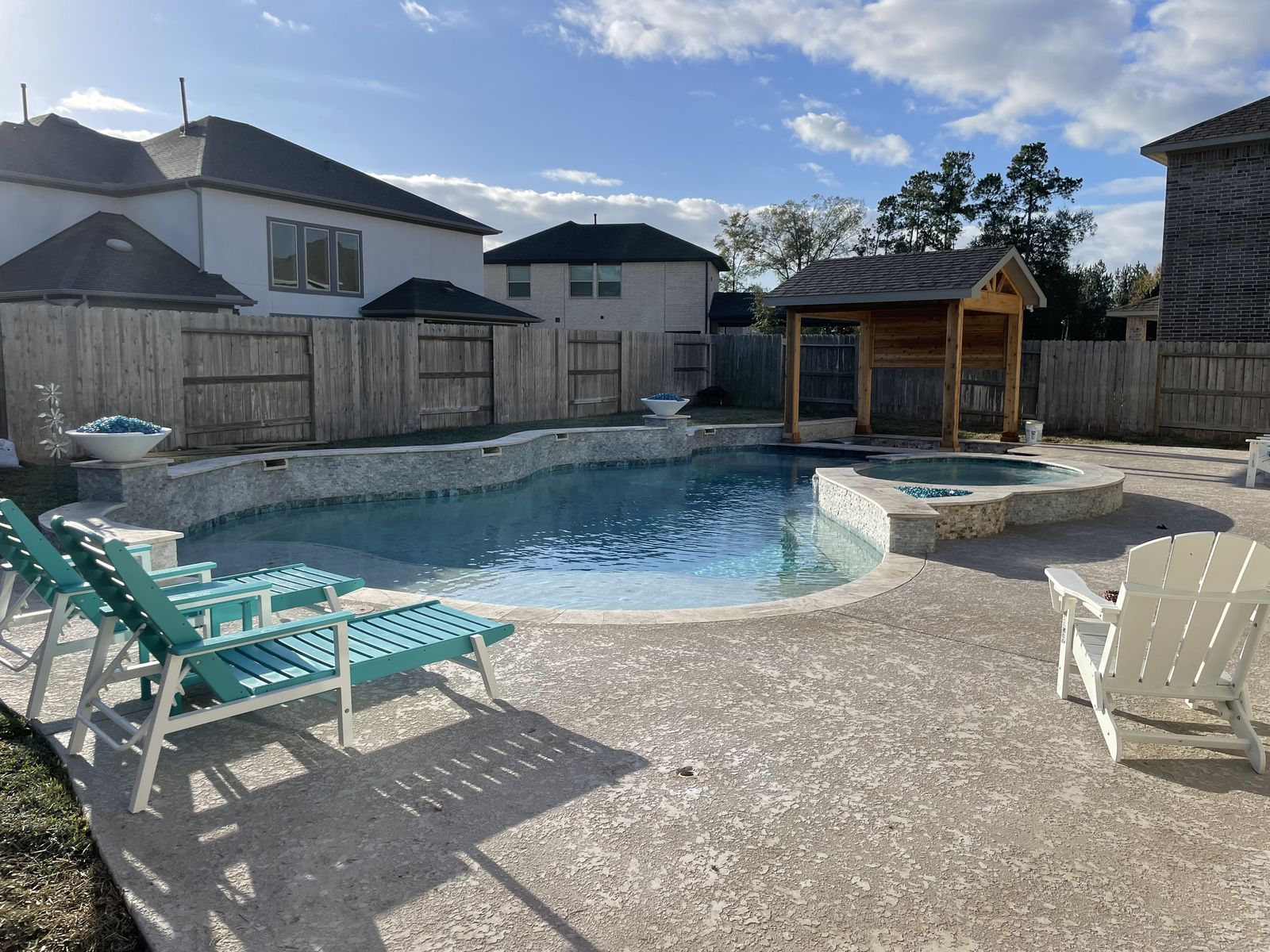 Freeform pool and raised spa with a cedar pergola behind