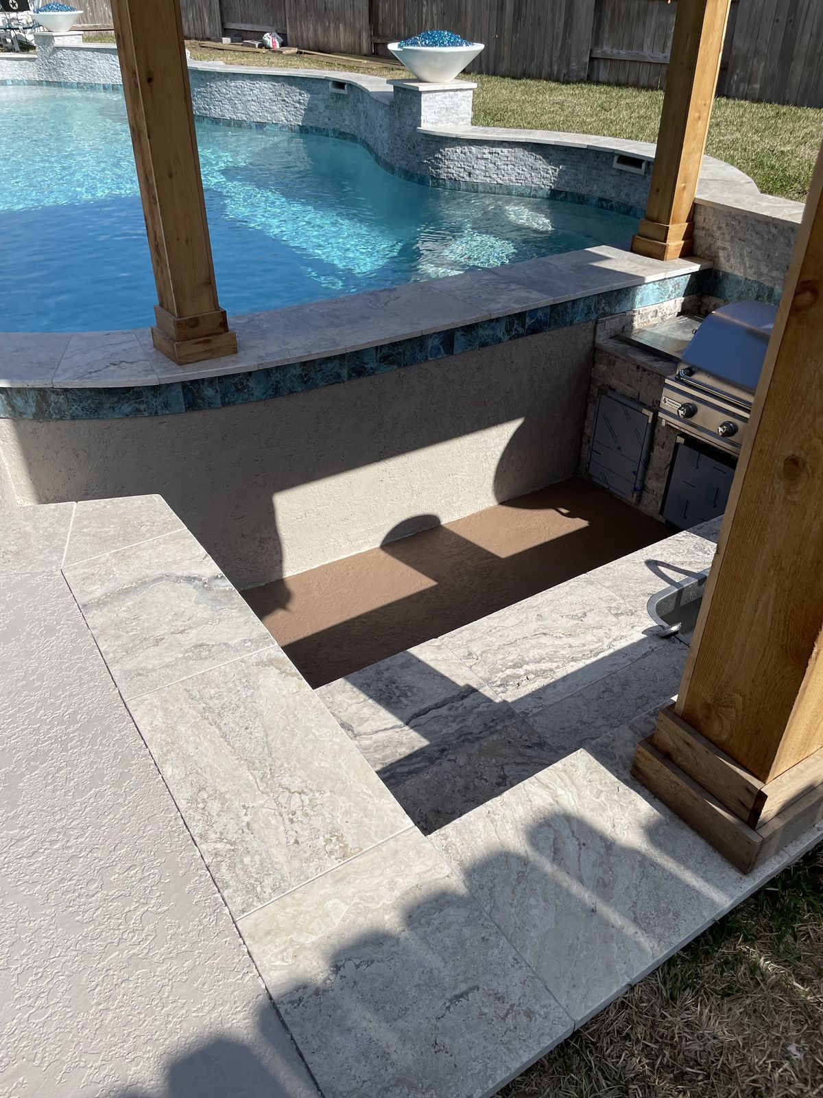 Pergola posts framing the sunken kitchen and the pool
