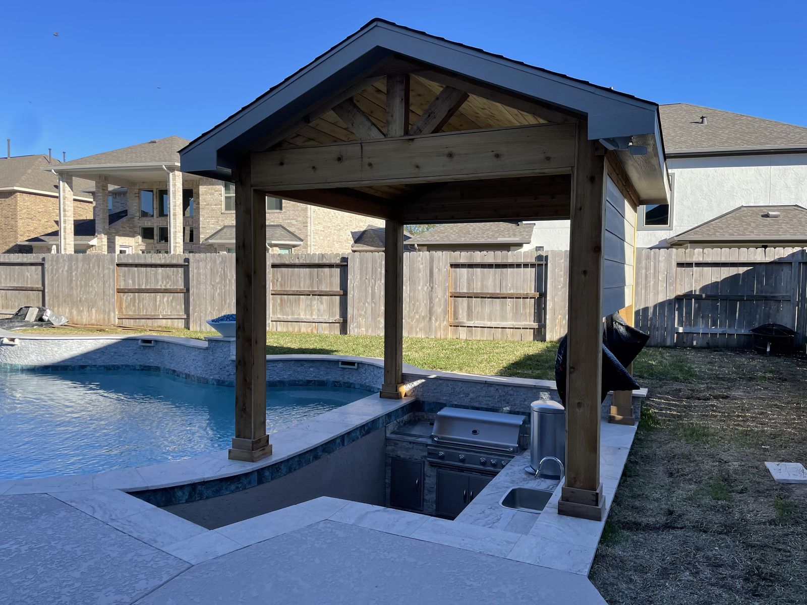 Cedar pergola over a sunken outdoor kitchen next to the pool