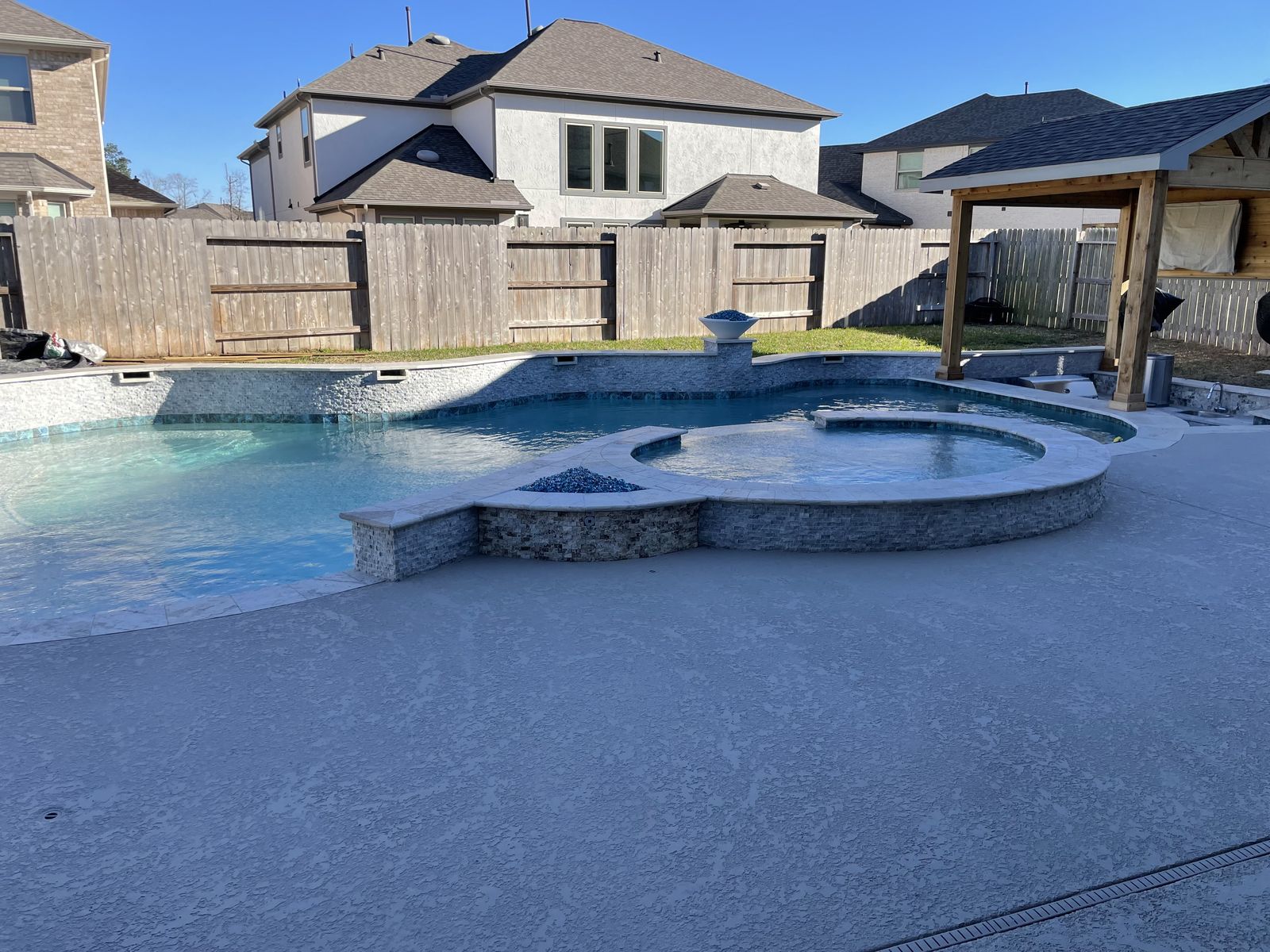 Wide view of a freeform pool, spa and pergola