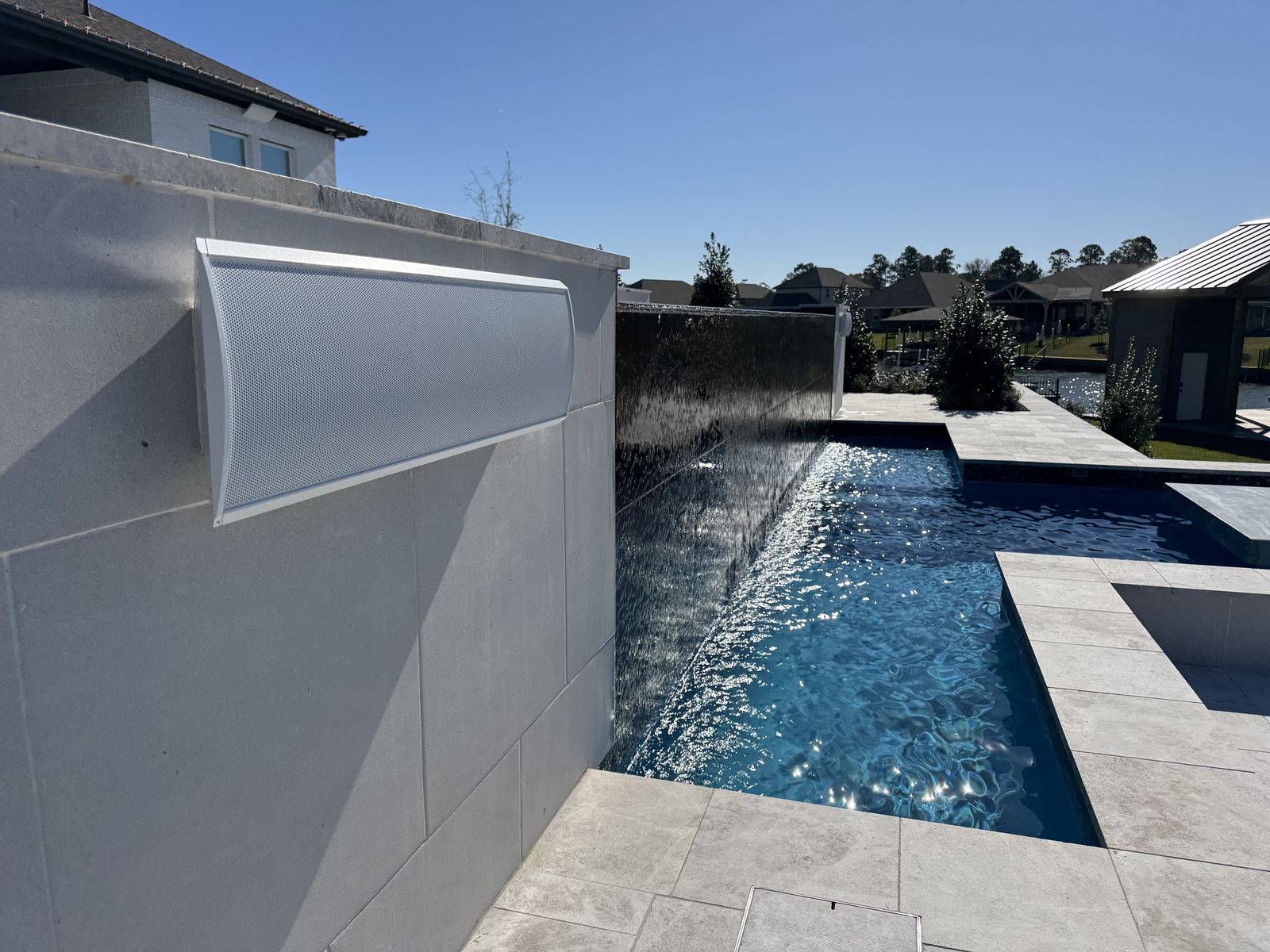 Sheer water wall spilling into a pool beside large-format tile
