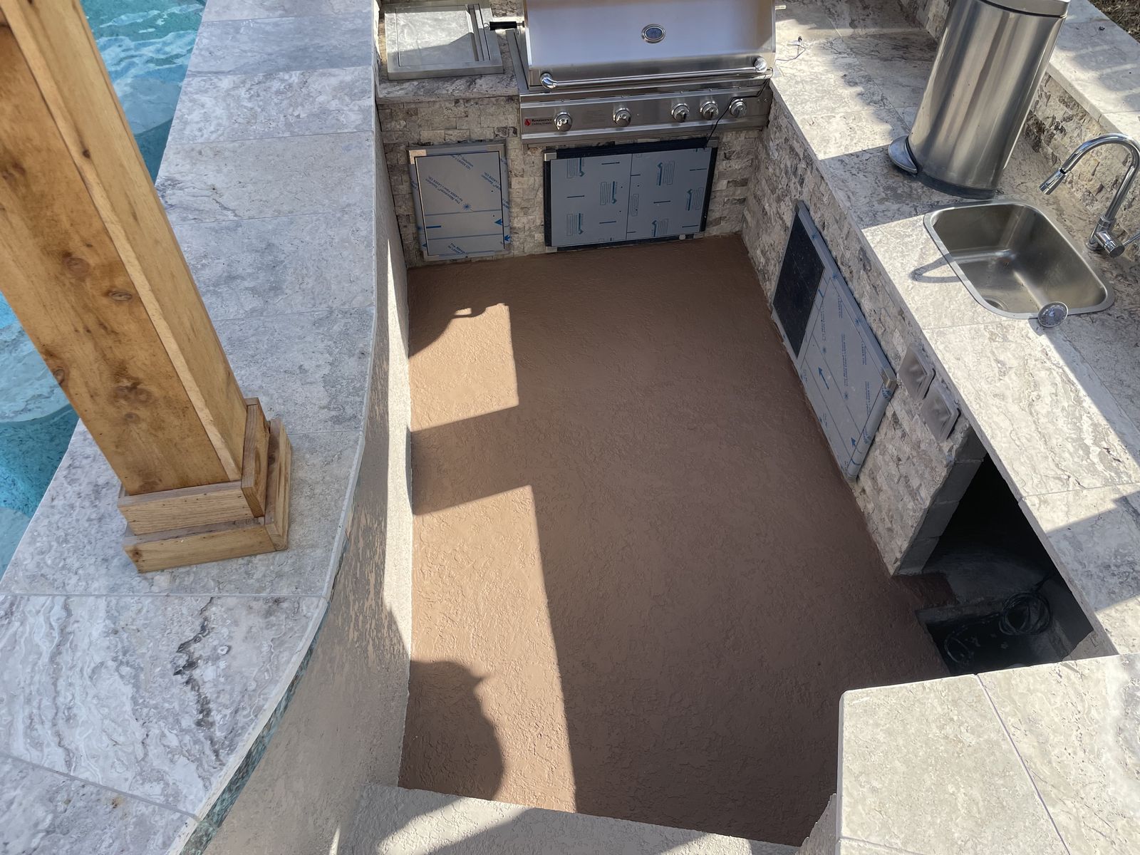 Sunken outdoor kitchen with grill, sink and travertine counters