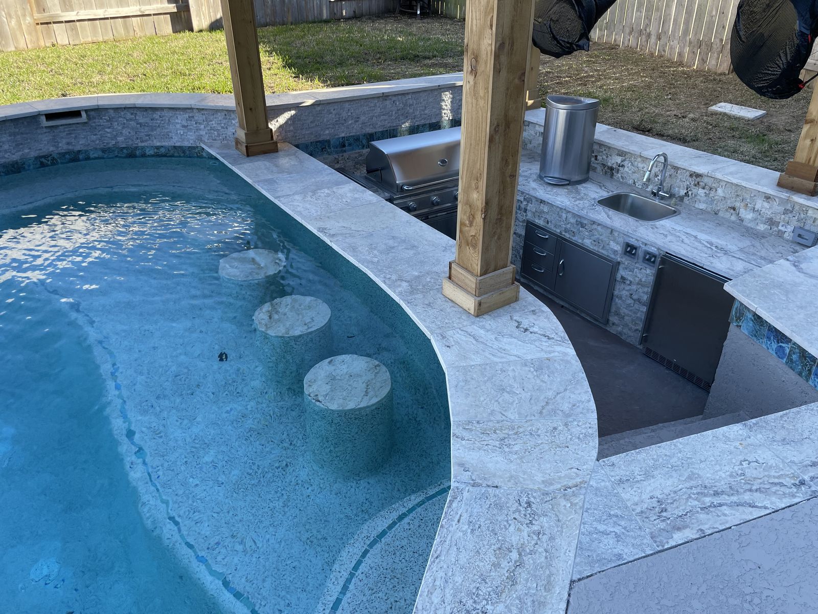 Swim-up bar stools set into the pool beside the outdoor kitchen