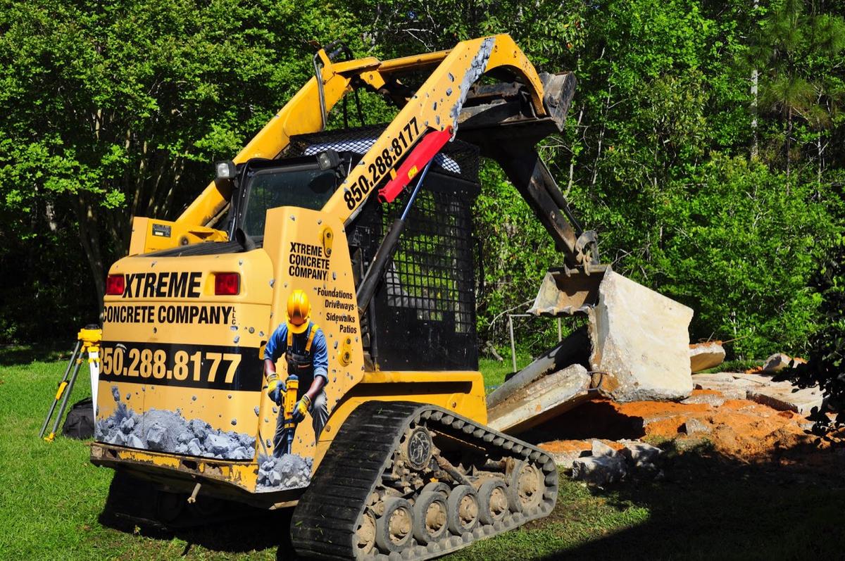 Xtreme Concrete Company skid steer lifting a broken concrete slab
